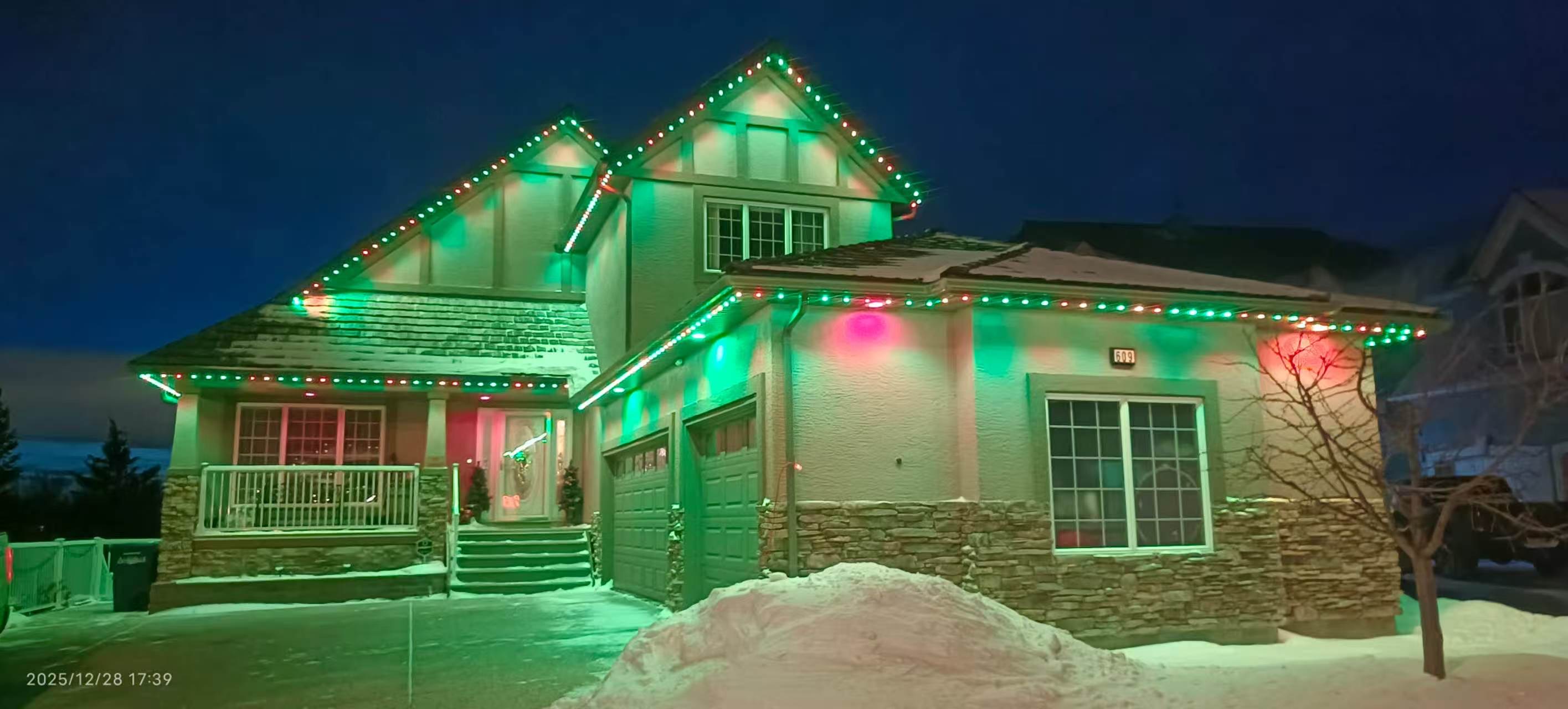 Red and green permanent eaves lighting on a snow-covered home