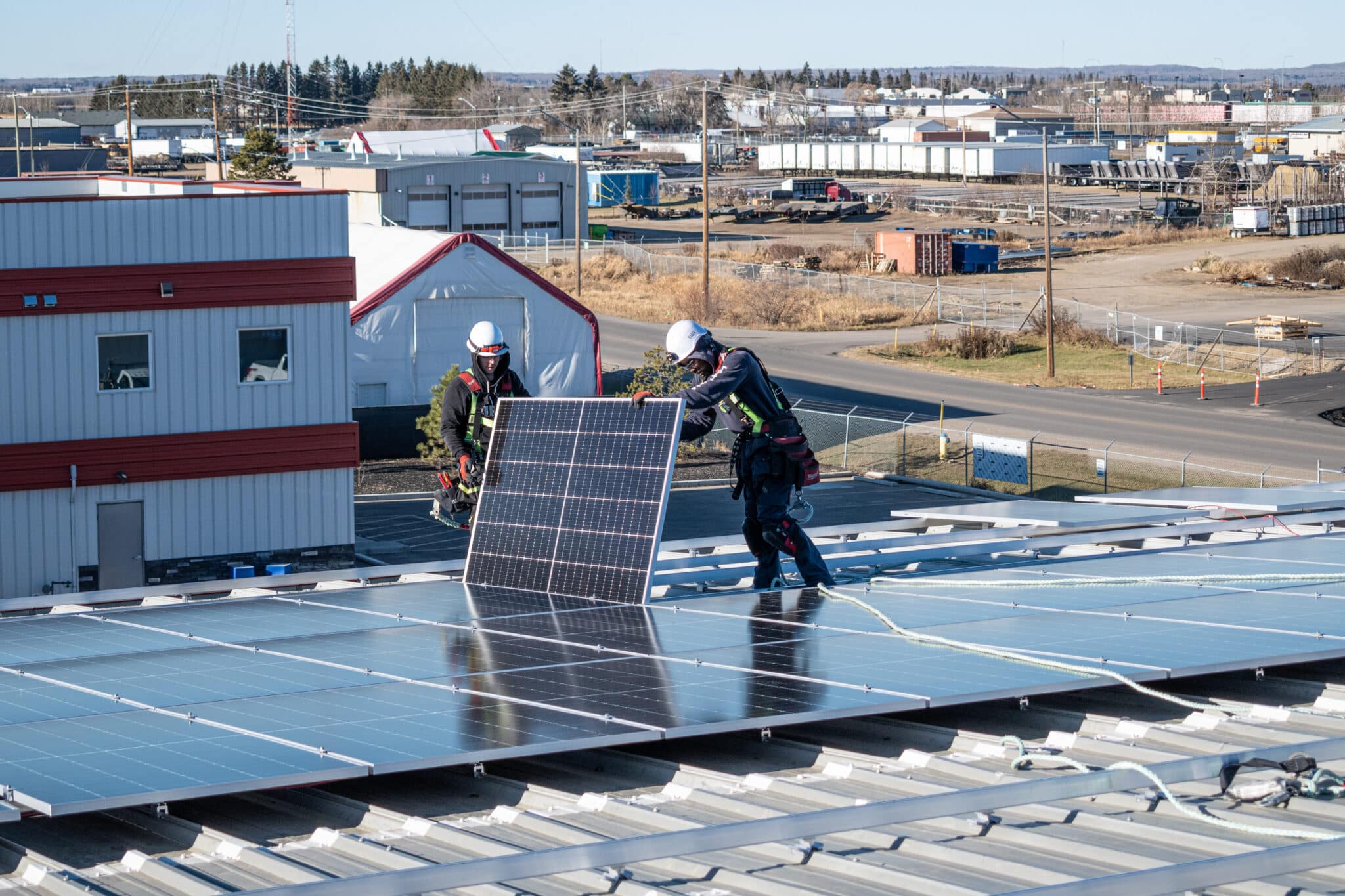 Installers placing solar panels on a commercial rooftop